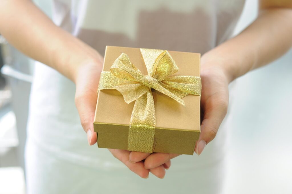 Hands holding a gold wrapped gift box
